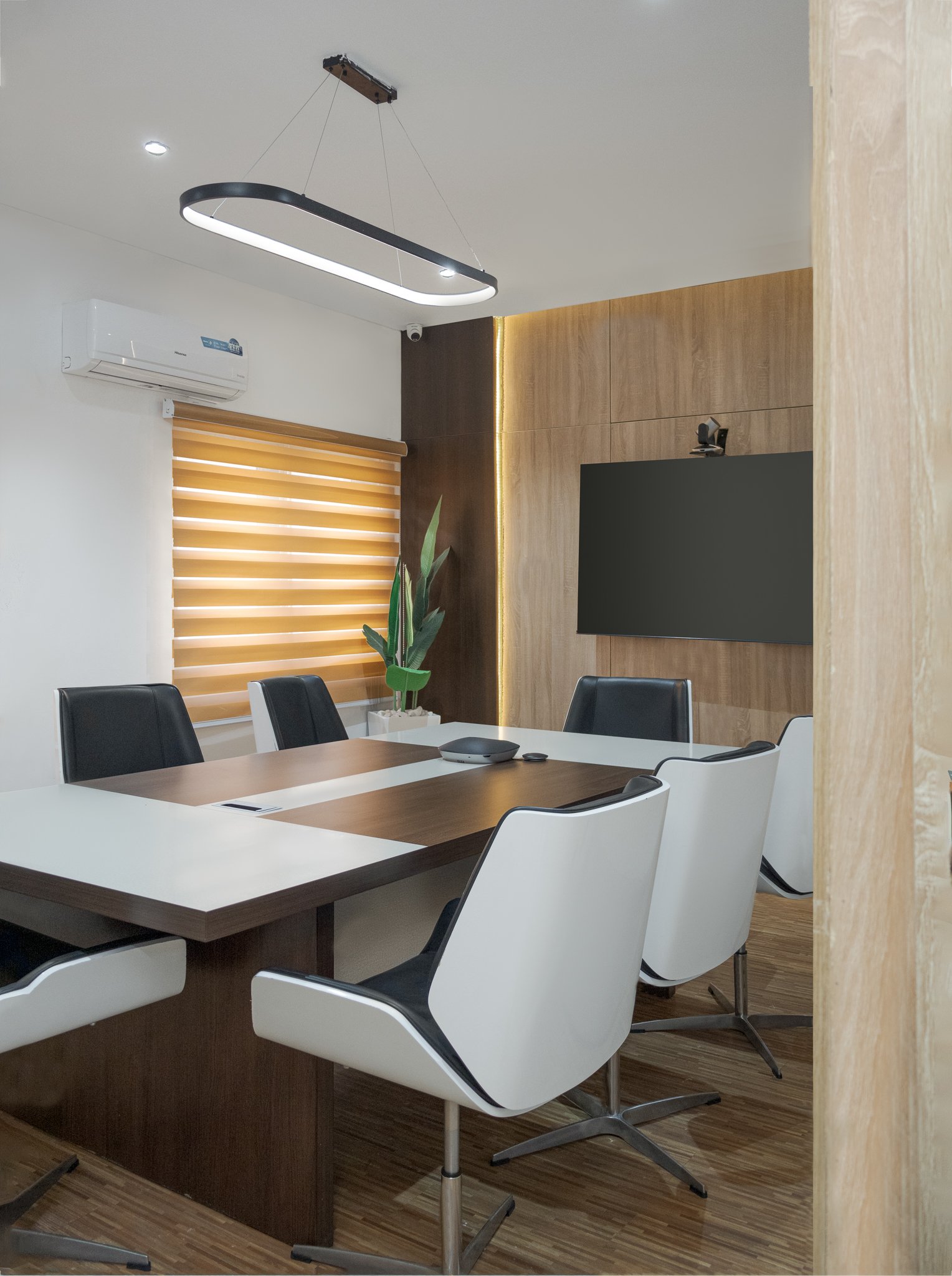 Boardroom with conference table, video conferencing screen and seating for eight