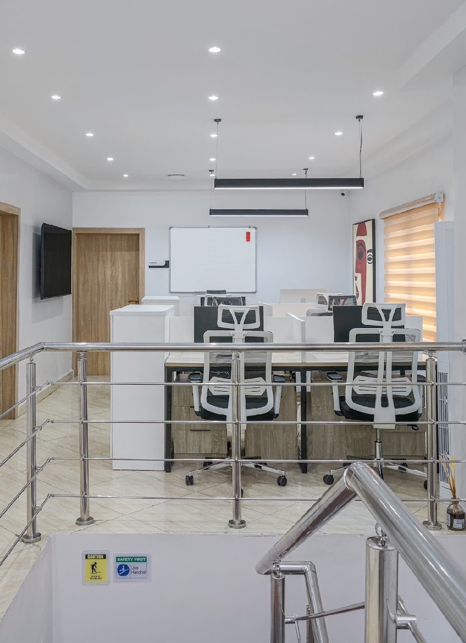 Open-plan workspace with staff desks and mezzanine railing