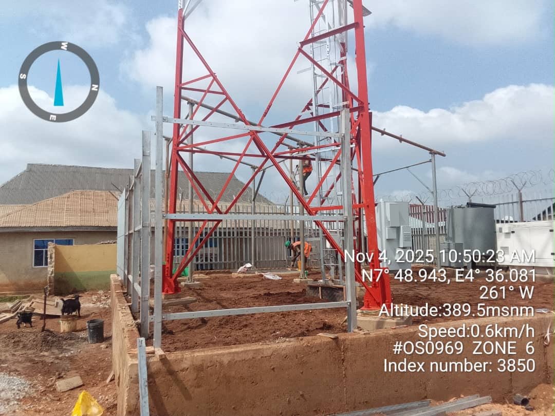 Steel lattice tower frame being erected with workers on site